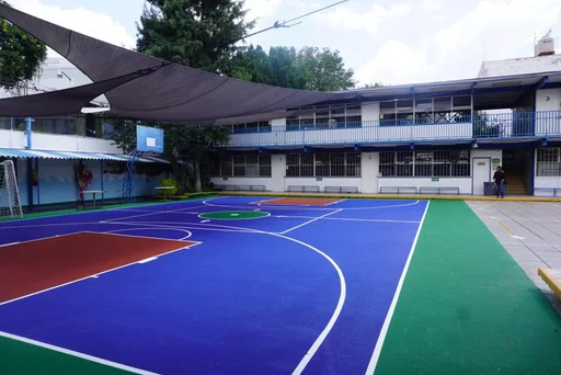 Patio multideportivo del colegio con cancha pintada y techo de sombra